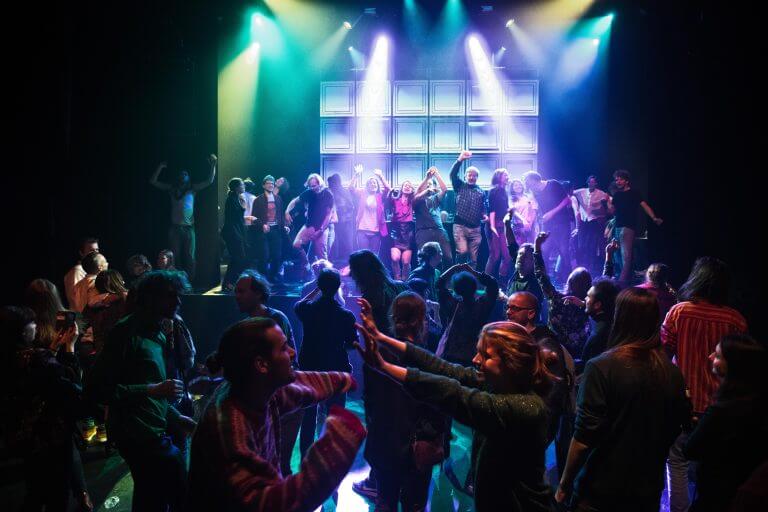 Een zaal vol dansende mensen en gekleurde lichten. Foto: Studio Schulte Schultz