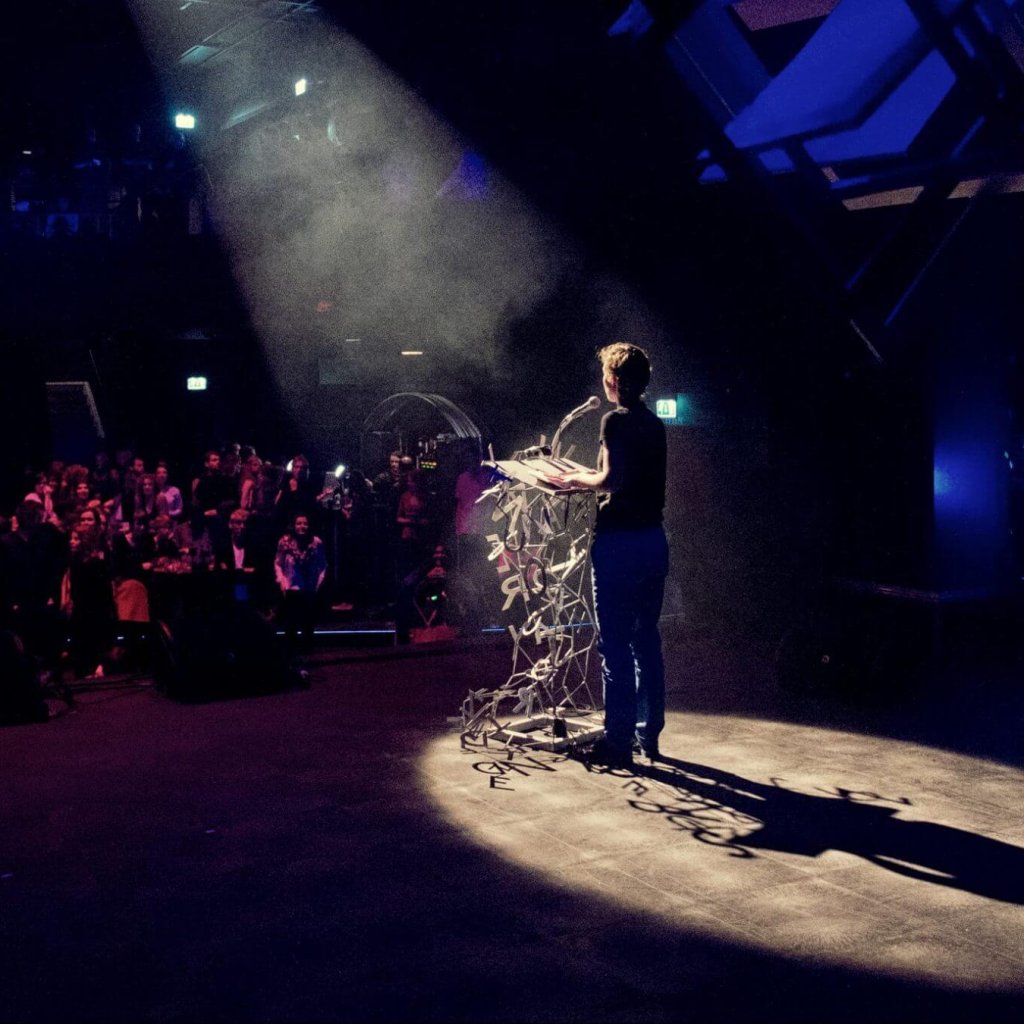 Over ons. Schrijver geeft voordracht voor publiek op Wintertuinfestival in Nijmegen. Foto: Studio Schulte Schultz